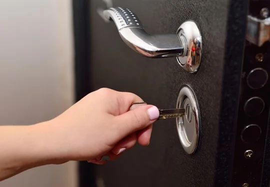 A hand inserts a key into a deadbolt