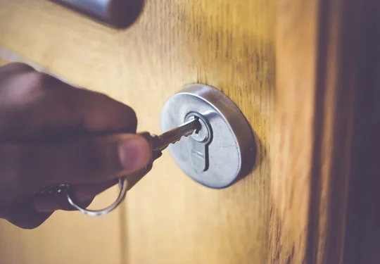 A hand inserts a key into a lock