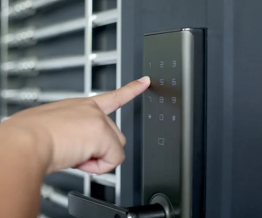 A hand presses keys on a door keypad