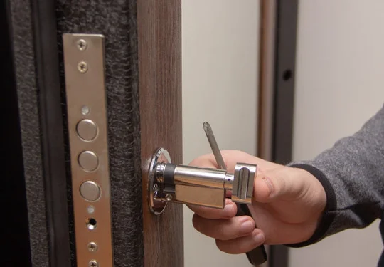 A hand holds a replacement deadbolt